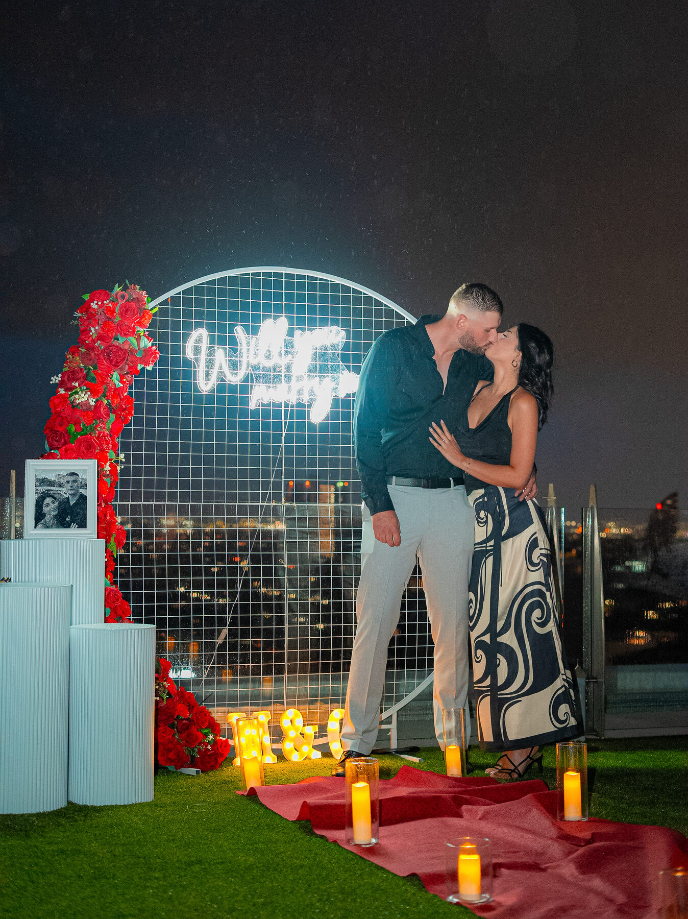 Rooftop proposal at night with neon sign