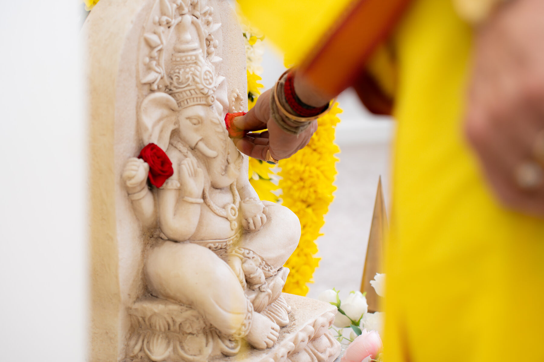 Hand placing flower at Ganesh idol during puja