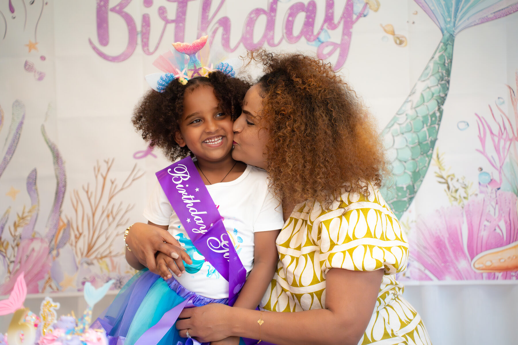 Mother kissing birthday daughter