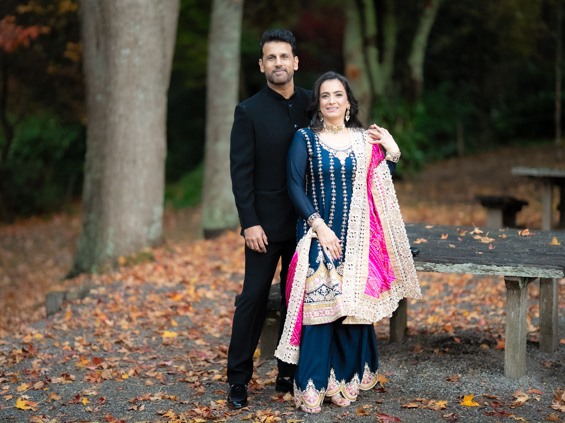Couple in formal Indian attire among autumn leaves